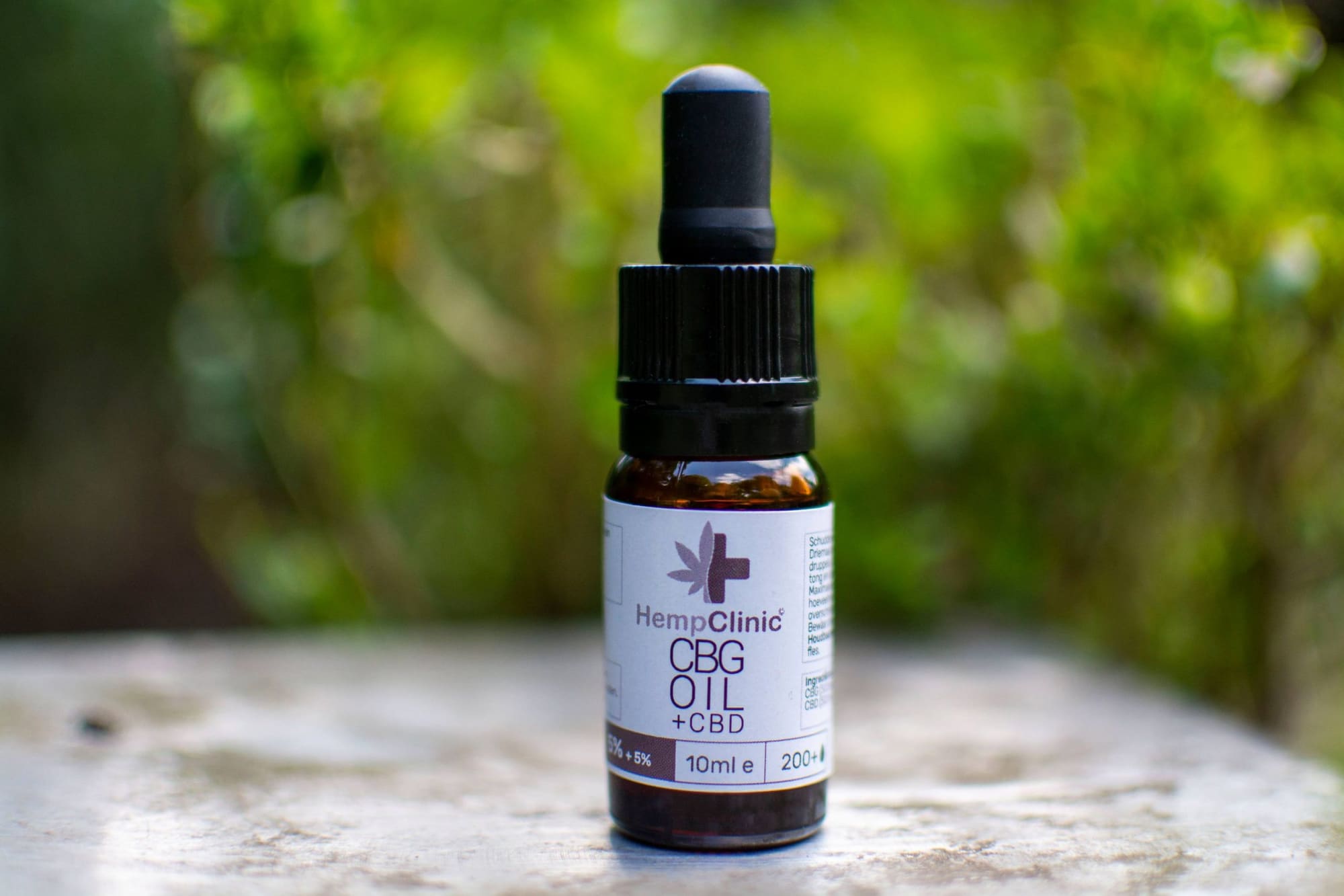 Flesje CBG-olie met CBD van Hemp Clinic op een stenen tafel buiten