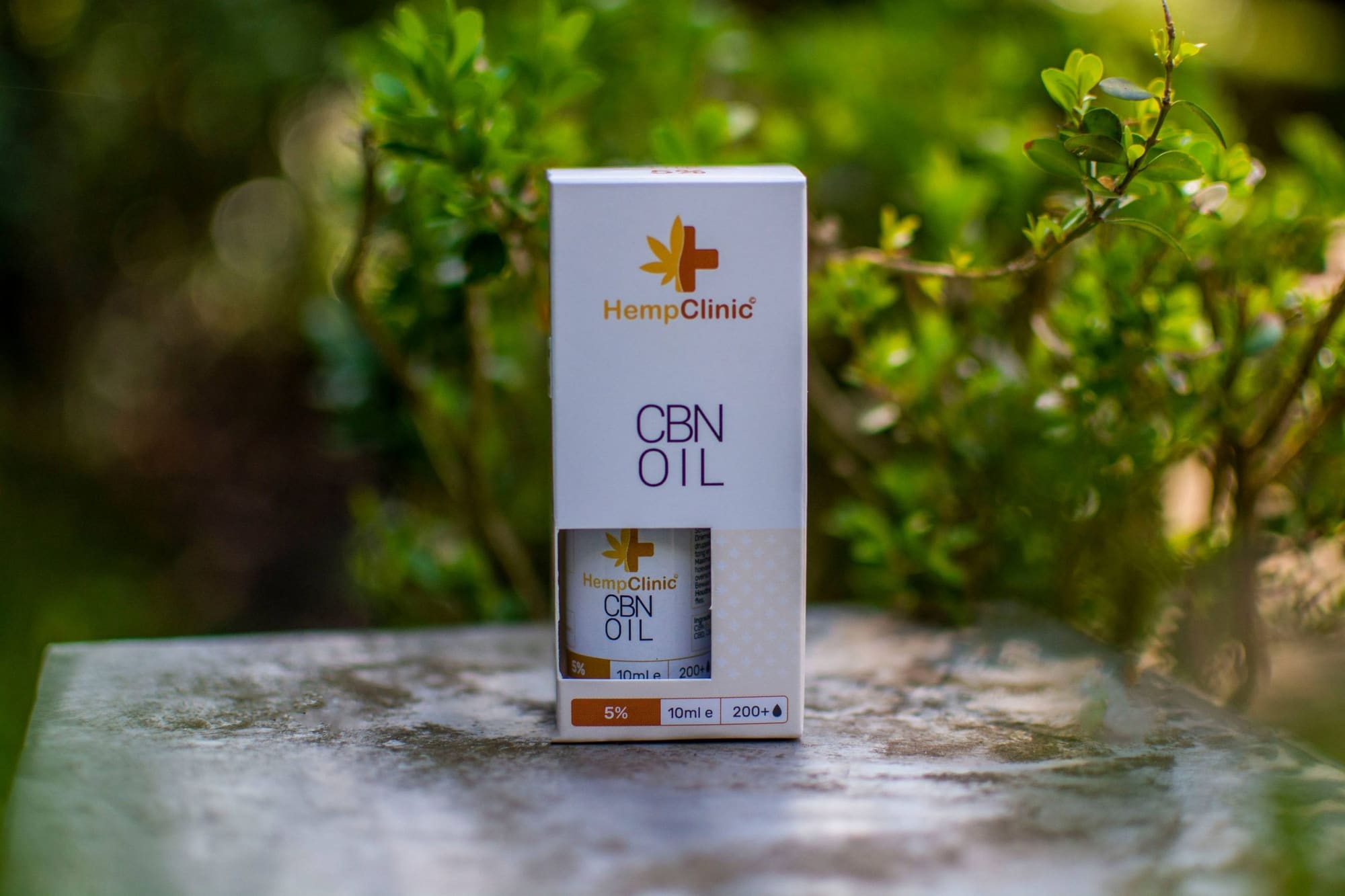 Doosje CBN-olie van Hemp Clinic op een stenen tafel buiten
