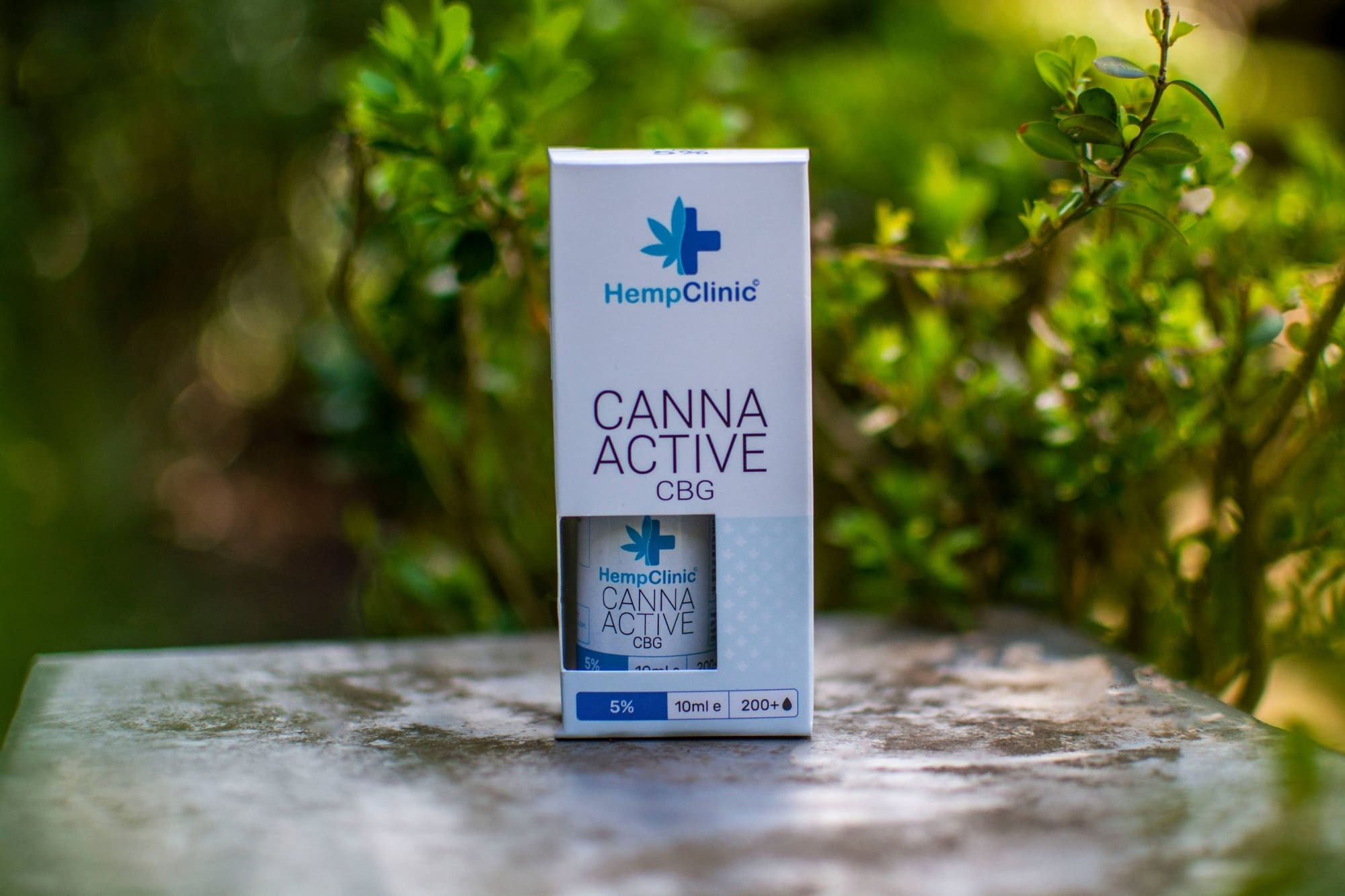 Doosje CannaActive CBG van Hemp Clinic op steen, met groen blad op de achtergrond